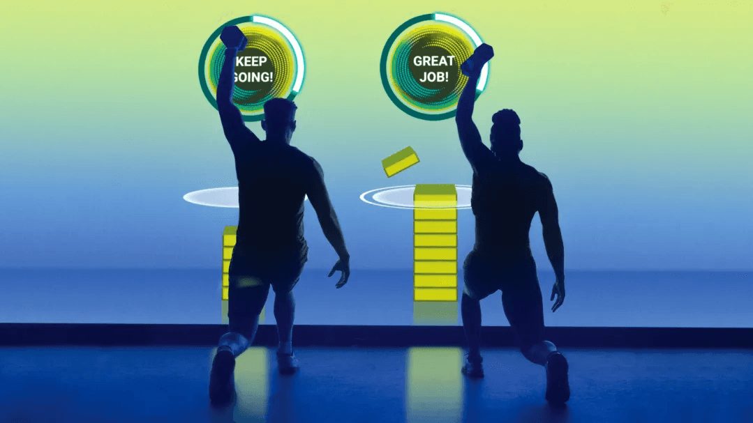 Two people in silhouette in front of a large studio screen showing colored score rings